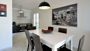 A modern kitchen with dark cabinetry, a white countertop, and a black pendant light.