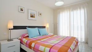 A neatly arranged bedroom with a bed, bedside lamps, a nightstand, and a window with curtains.