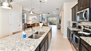 Una cocina moderna con encimeras de granito, electrodomésticos de acero inoxidable e iluminación colgante.