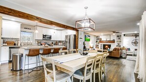Una cocina amplia con una isla central, vigas de madera y un comedor con una mesa larga y sillas.