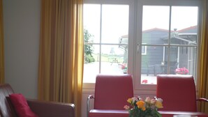 Une pièce avec un canapé rouge, une table ornée d’un vase de fleurs et deux chaises rouges.