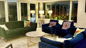 A living room with a green sofa, two blue armchairs, a small round table, and a glass door leading outside. - Beautiful 5 bedroom home in Mid Ulster- Magherafelt  (County Derry)