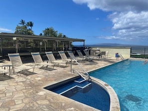 A swimming pool with lounge chairs and a covered area.