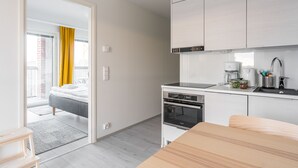 A modern kitchen with a built-in oven and a dining area with a wooden table. - Hiisi Homes Turku Elin Sagerin kuja (Turku)