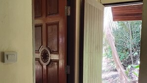 A room with a wooden door, a tiled floor, and a view of a garden outside. - Garden Lodge Bungalow (Klong Son)