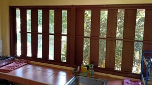 A kitchen with a sink, a window with a view of greenery, and a tiled floor. - Garden Lodge Bungalow (Klong Son)