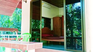 A room with a wooden bed, a green chair, and a table with a purple rug. - Garden Lodge Bungalow (Klong Son)