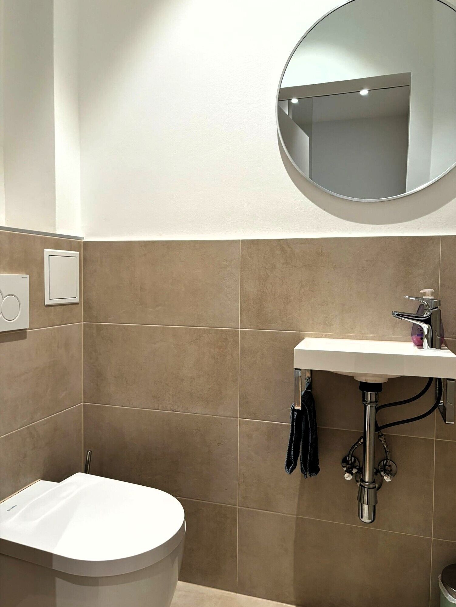 Un baño moderno con inodoro, lavamanos y espejo.