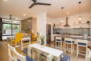 A modern kitchen with a dining area, a ceiling fan, and a large window.