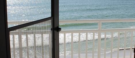 A view from a balcony overlooking a beach with a clear sky.