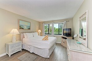 A hotel room with a bed, a television, a dresser, a mirror, and a painting on the wall.