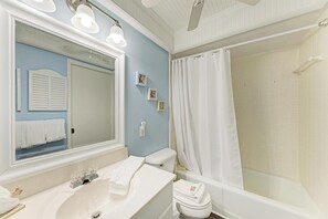 A bathroom with a sink, mirror, toilet, and shower.