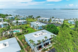 A coastal resort with multiple blue buildings, a swimming pool, and palm trees.