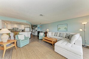 A modern living room with a sofa, coffee table, and a dining area with chairs. - West Bay Cove 226 · Kayak Launch · For Sale (Holmes Beach)