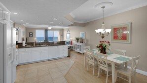 A spacious kitchen with white cabinets, a granite countertop, and a dining area with a white table and chairs.