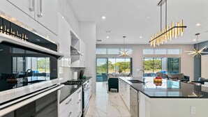 Una cocina moderna con una isla grande, electrodomésticos integrados y vistas al exterior.