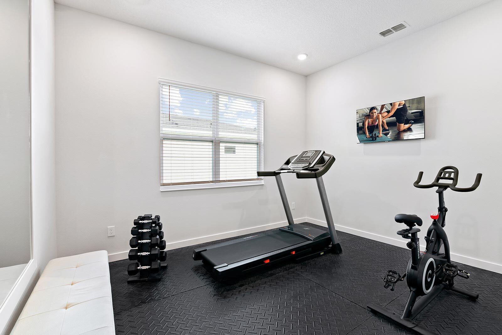 Ein Heimfitnessraum mit Laufband, Ergometer und Kurzhanteln.