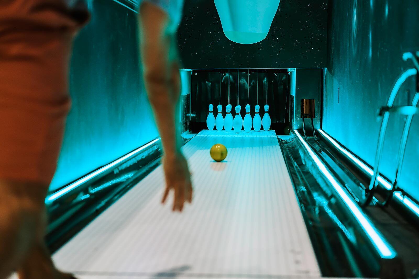 A bowling alley with a lane, bowling pins, and a bowling ball.