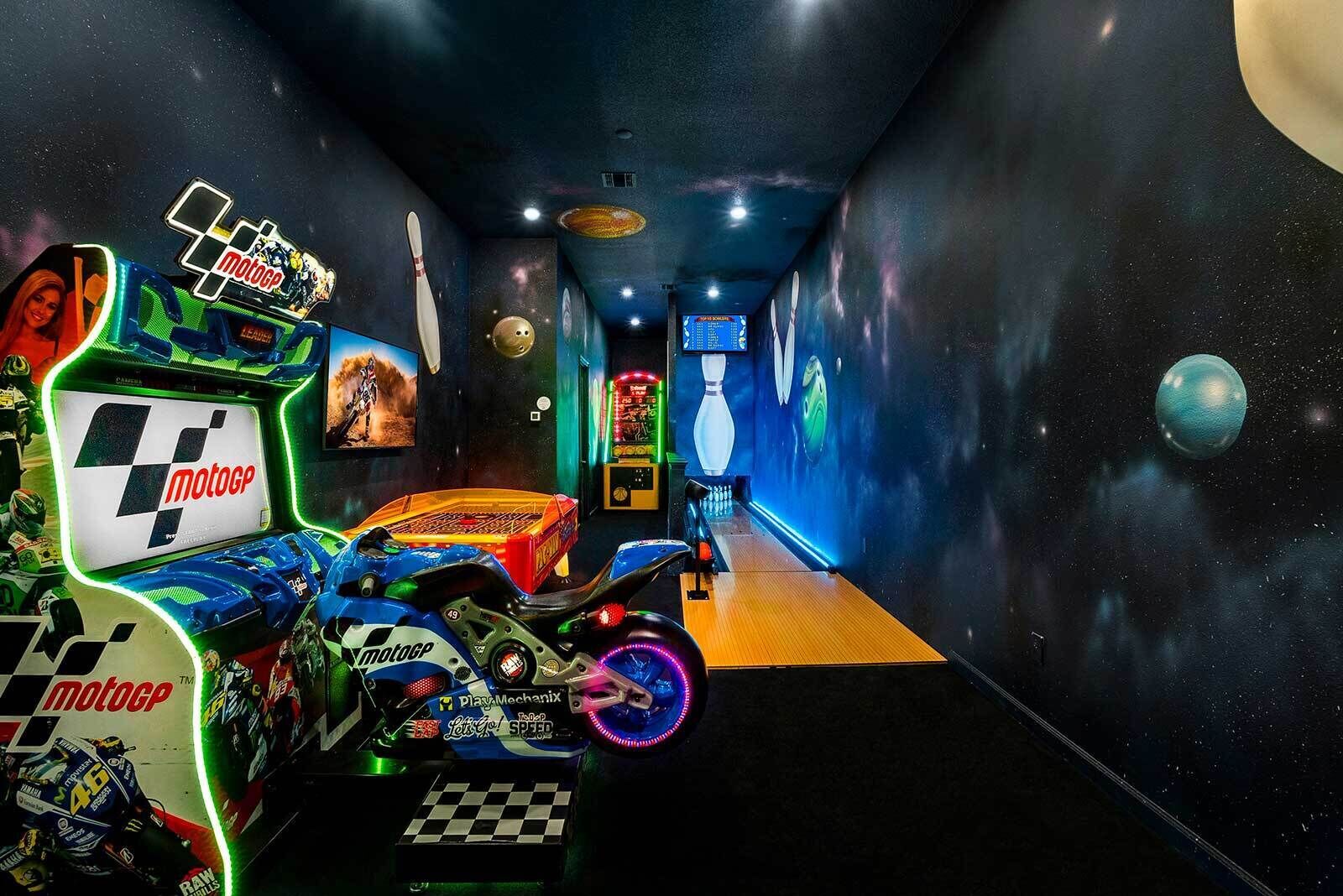 A bowling alley with a space-themed mural, a bowling ball, and a bowling lane.