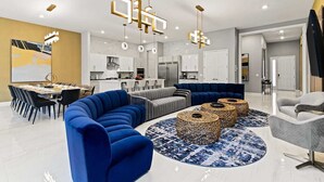 A modern living room with a blue sectional sofa, a grey couch, and a round coffee table with woven side tables. - Homes by Villatel | Trampoline RM, Bowling, Ocean Theme BR, Theater, Near Parks (Davenport)
