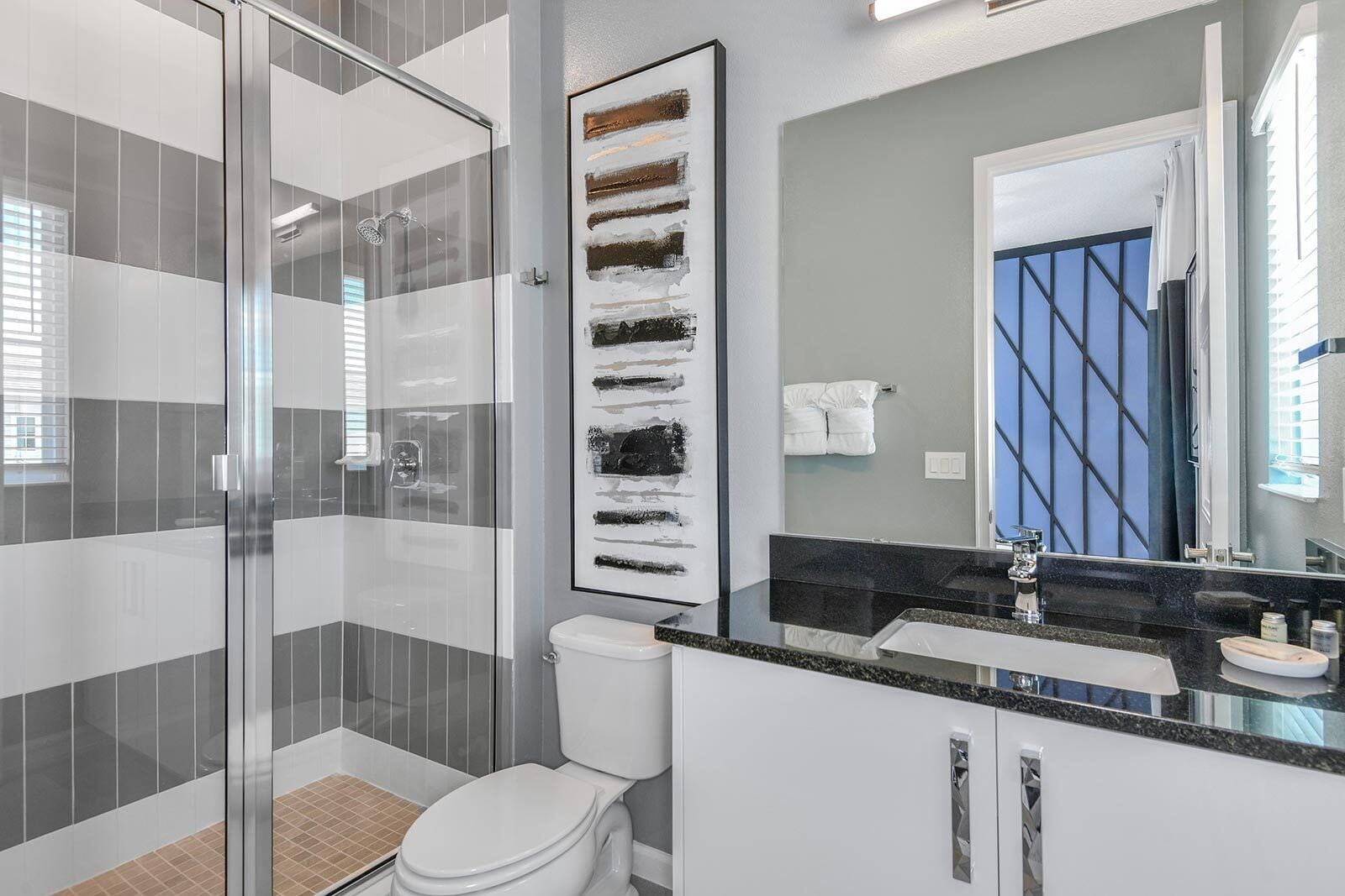 Une salle de bain moderne avec une douche à parois de verre, des toilettes blanches et un plan de toilette noir avec un lavabo.