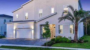 A two-story house with a garage, a stone accent wall, and a palm tree in the front yard. - Feature-Rich Home w Superhero Theme BR, Huge Arcade & Theater - Near Disney (Davenport)