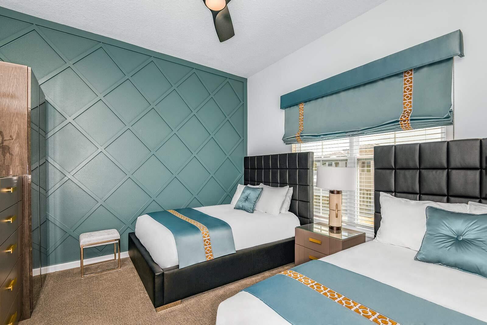 A modern hotel room with a large bed, a smaller bed, a nightstand, a lamp, and a wardrobe.