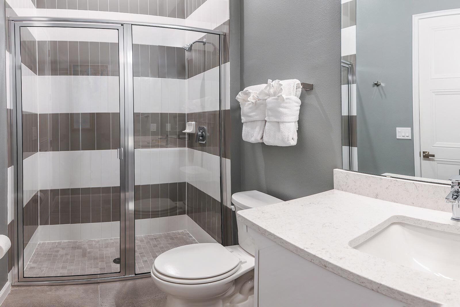 Ein modernes Badezimmer mit Duschkabine aus Glas, einer weißen Toilette und einem мрамор Waschbecken.