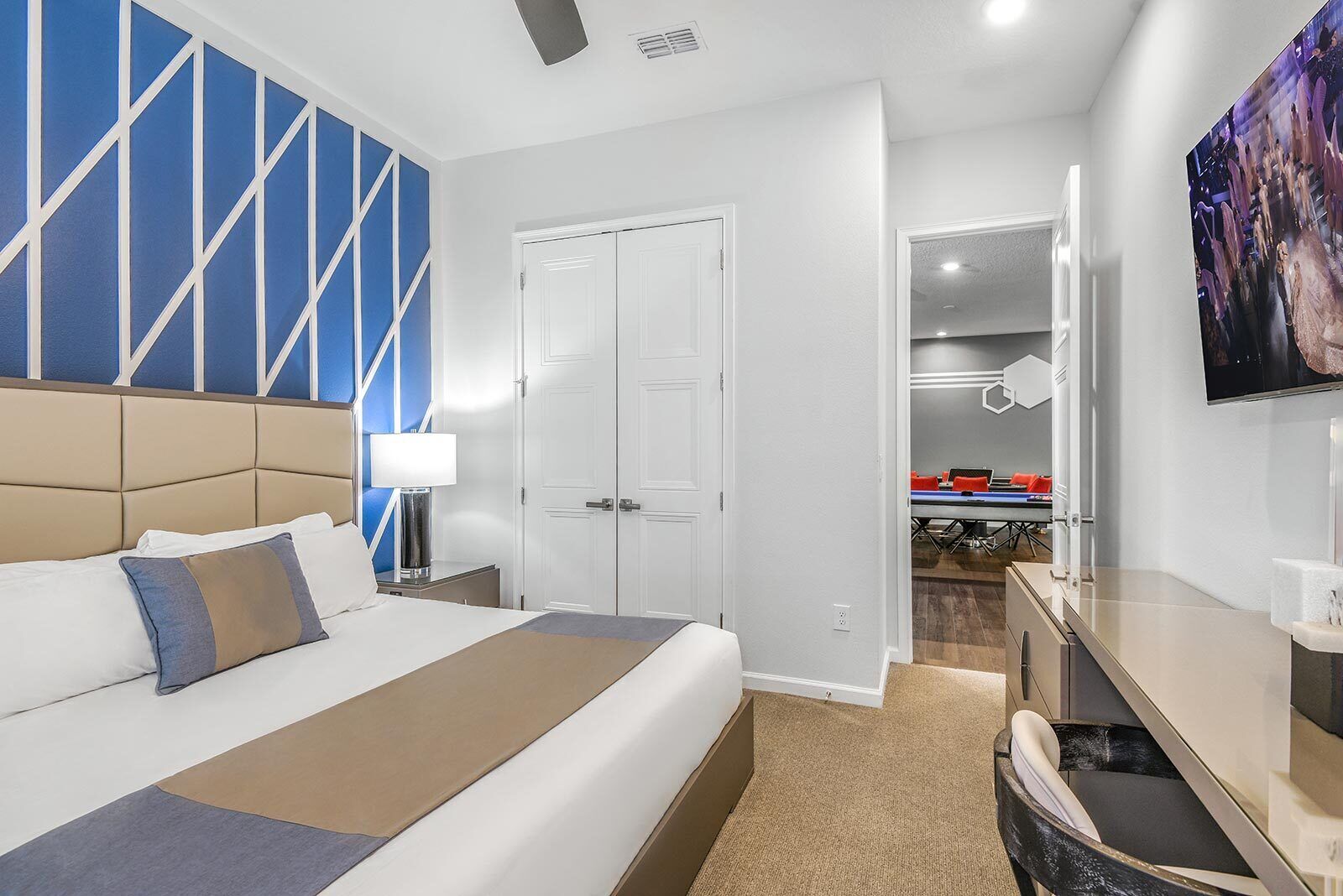 Une chambre d’hôtel avec un grand lit, un bureau, une chaise, une télévision, une armoire et une salle de bain visible à travers une porte ouverte.