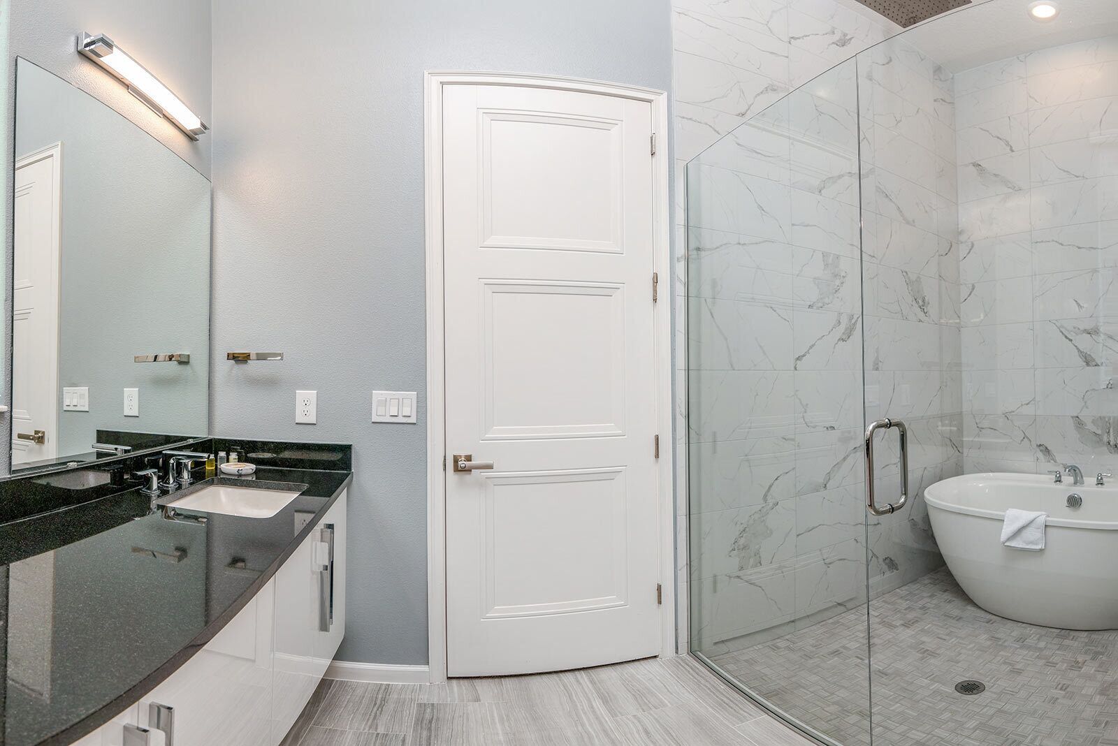 Une salle de bain moderne avec une douche à parois de verre, un lavabo blanc et un grand miroir.