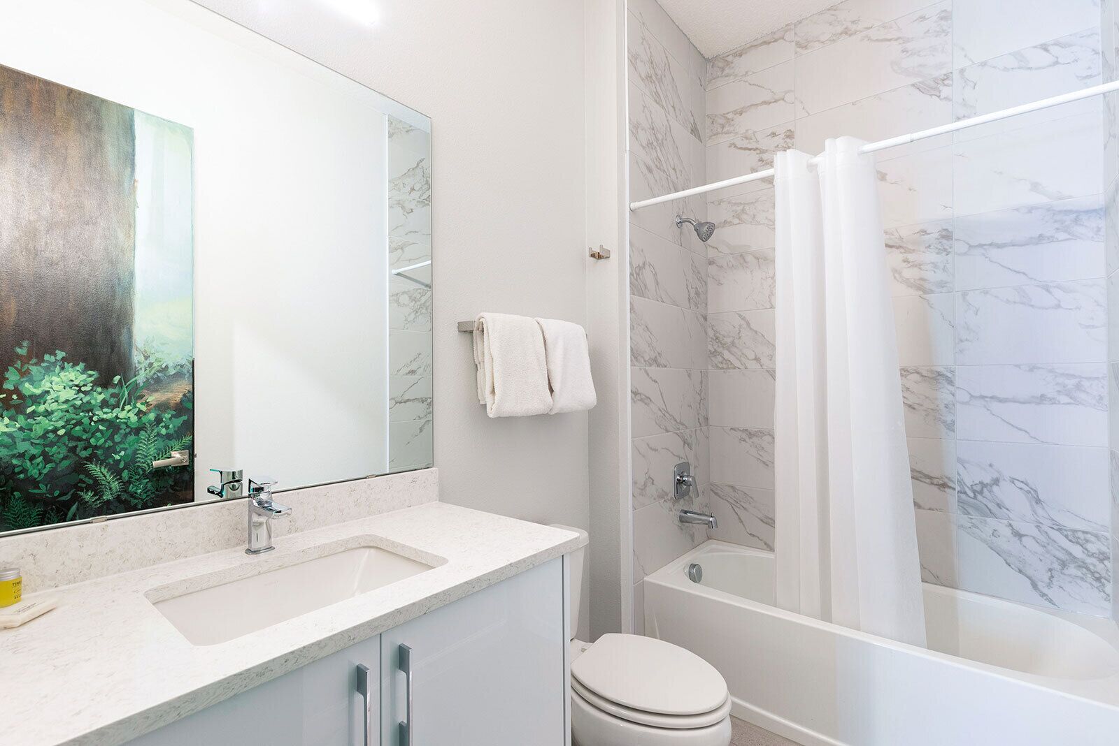 Une salle de bain avec une douche en marbre, des toilettes, un lavabo avec un miroir et un porte-serviettes.