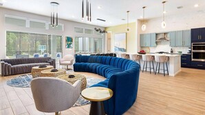 A modern living room with a blue sectional sofa, a grey armchair, and a patterned coffee table.