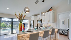 Una cocina moderna con armarios blancos, electrodomésticos de acero inoxidable y una isla grande con taburetes de bar.