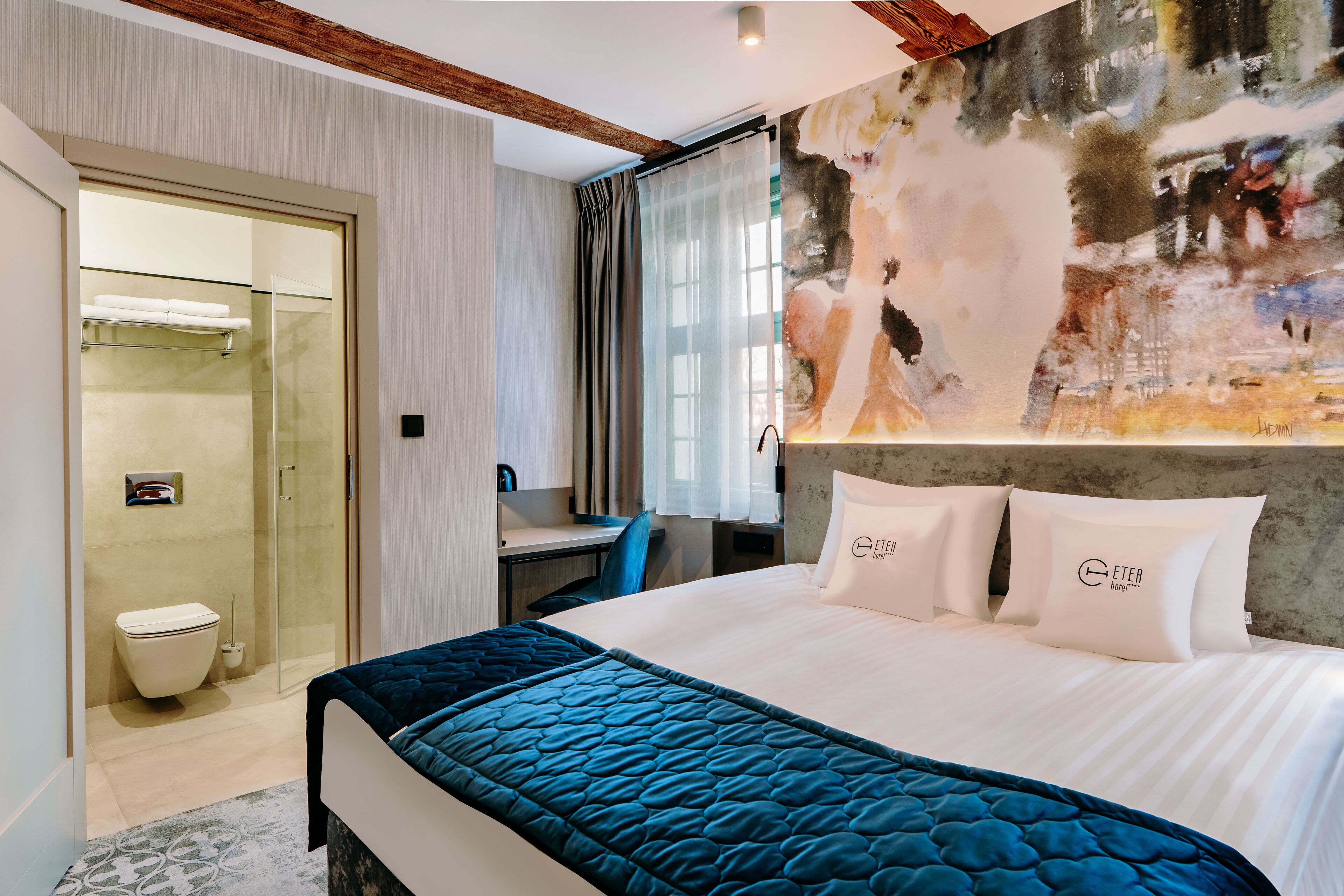 A modern hotel room with a large bed, a desk, and a shower area.