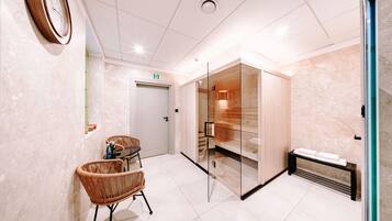 A modern bathroom with a wooden sauna, a glass partition, and wicker chairs.