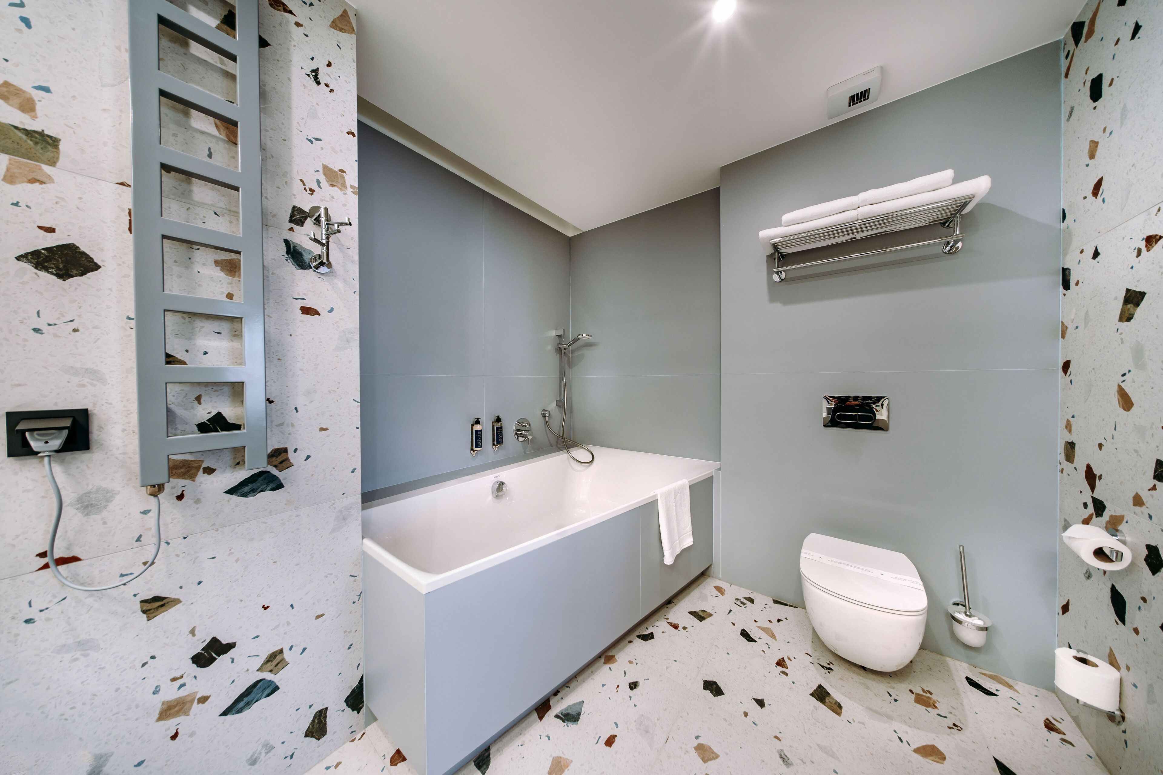 Une salle de bain moderne avec une baignoire sur pieds, des toilettes et un porte-serviettes.