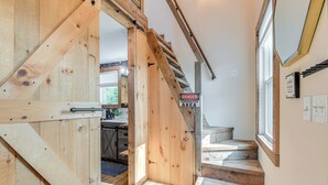 Eine Holztreppe mit einem 'DANGER RESTRICTED AREA'-Schild, das zu einem Raum mit einem großen Fenster und einer Tür führt.