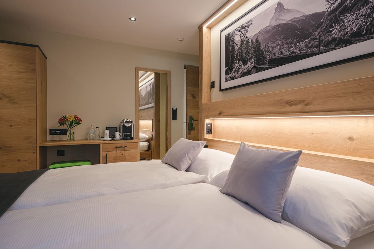 A hotel room with a large bed, a wooden headboard, a desk with a coffee maker, and a framed picture on the wall.