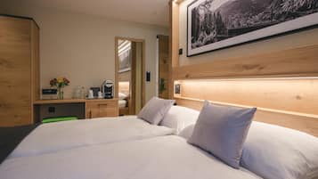A hotel room with a large bed, a wooden headboard, a desk with a coffee maker, and a framed picture on the wall.