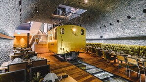 A restaurant with a vintage train carriage as a centerpiece, wooden flooring, and stone walls. - Hotel Tannenhof (Zermatt)