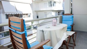 A balcony with two wooden chairs and a table, a white tablecloth, and a pink lantern. - Elegant & Spacious  Apt. with Sea View (Piraeus)
