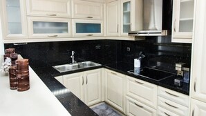 A modern kitchen with white cabinets, black countertops, and stainless steel appliances. - Elegant & Spacious  Apt. with Sea View (Piraeus)
