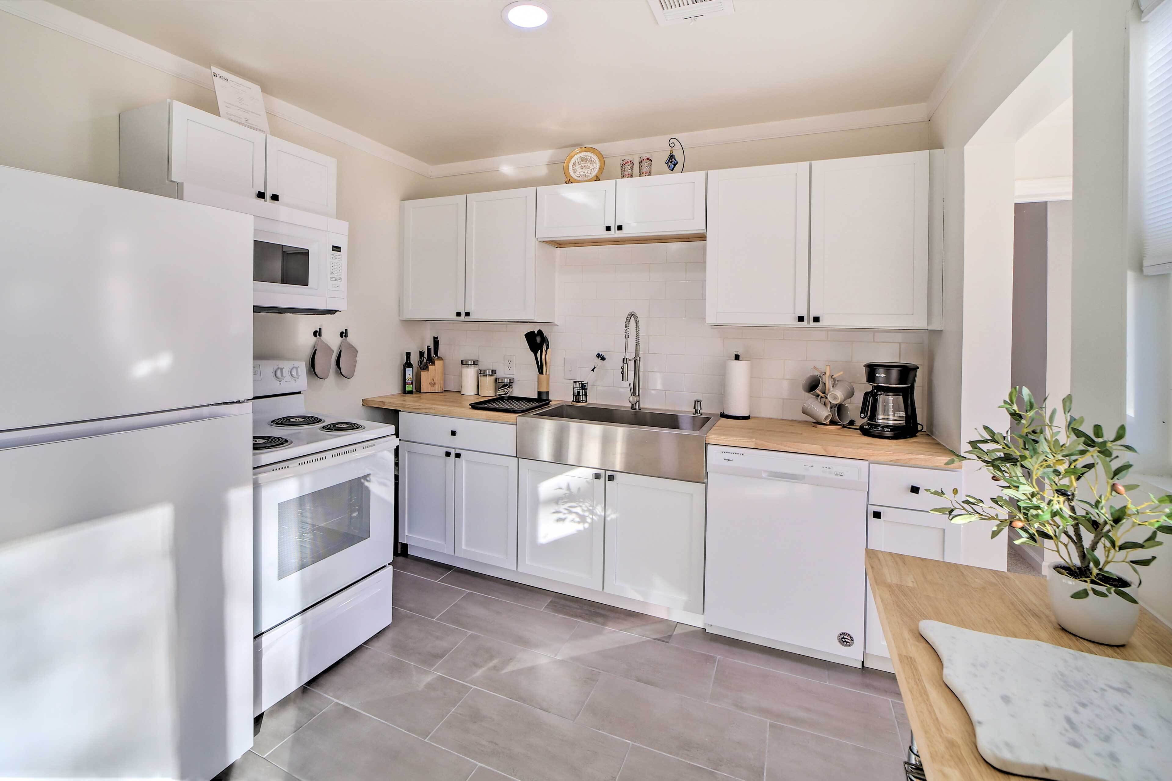 A modern kitchen with white cabinets, stainless steel appliances, and a wooden countertop.