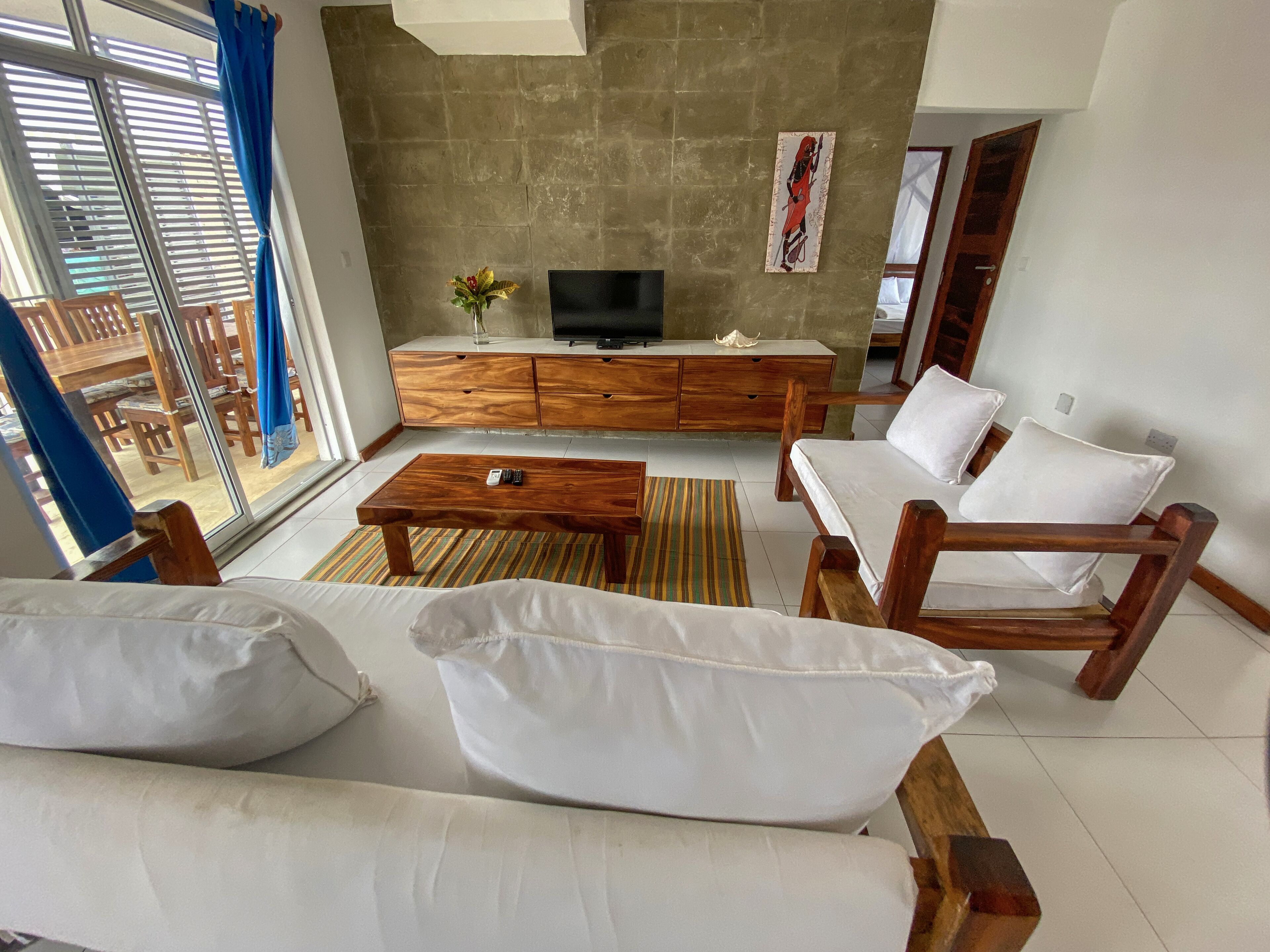 Uma sala de estar com sofá, mesa de centro, televisão e armário de madeira.
