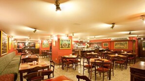 Un restaurante con varias mesas y sillas, una zona de bar y una sección de estar con un sofá.