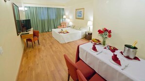 Habitación de hotel con cama, escritorio, silla, mesa lista para comer y televisor.