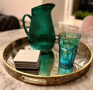 A tray with a green pitcher, a blue glass, and a stack of white plates.