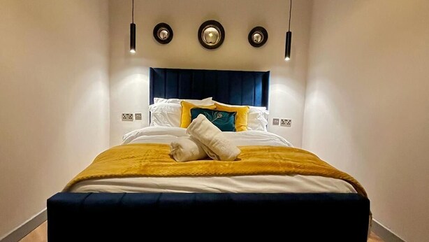 Ett hotellrum med en säng, sänglampor och en väggmonterad lampa.