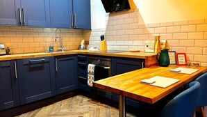 A kitchen with blue cabinets, a wooden countertop, a herringbone floor, and a black oven.