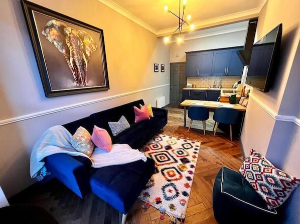 A modern living room with a sofa, patterned rug, and a kitchen in the background.
